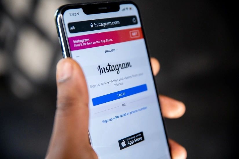 Image of a hand holding a phone displaying Instagram's homepage